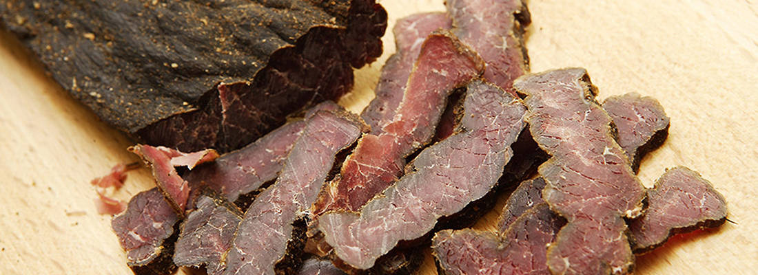 close up of Biltong sitting on a wooden board 