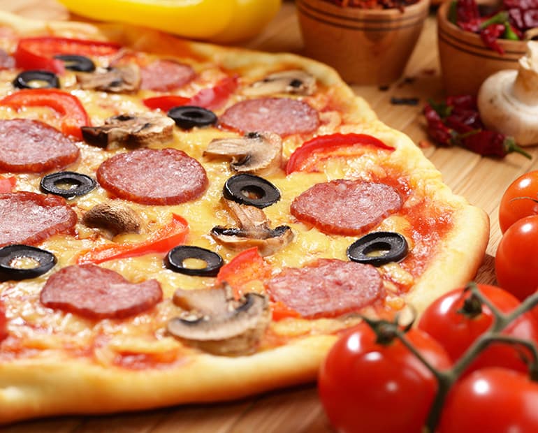Pizza on wooden board with bunch of tomatoes 