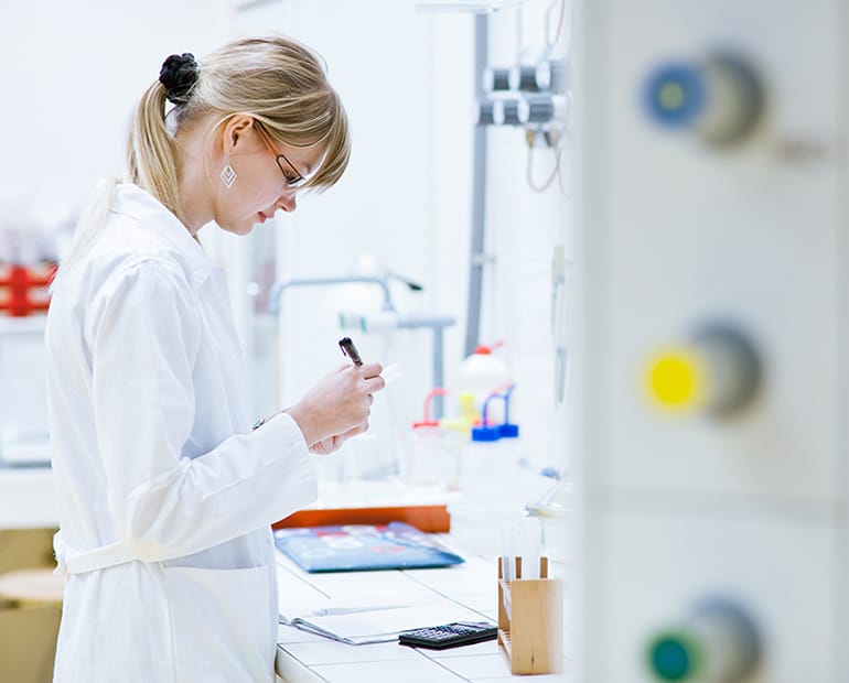 Female researcher in white lab coat labels a lab sample