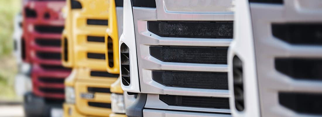 close up of front grills of four articulated trucks