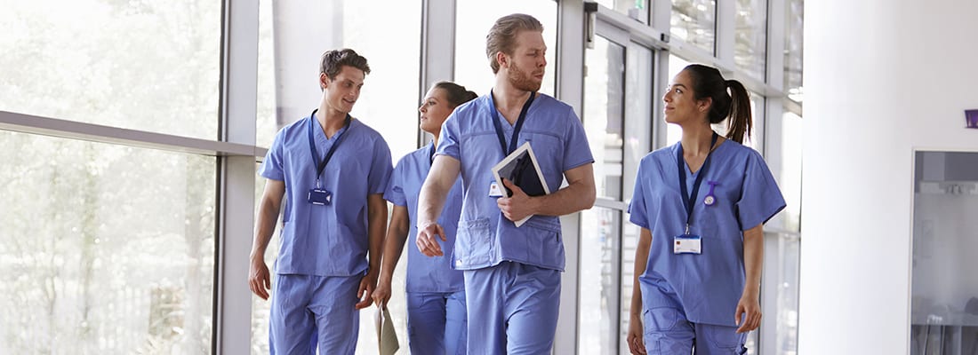 Group of doctors in scrubs walk down a hospital corridor 