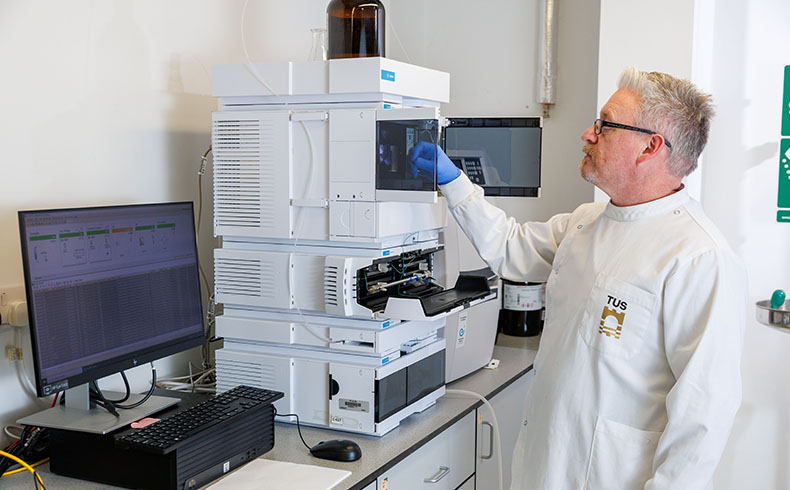 research engineer in white lab coat operating equipment in lab