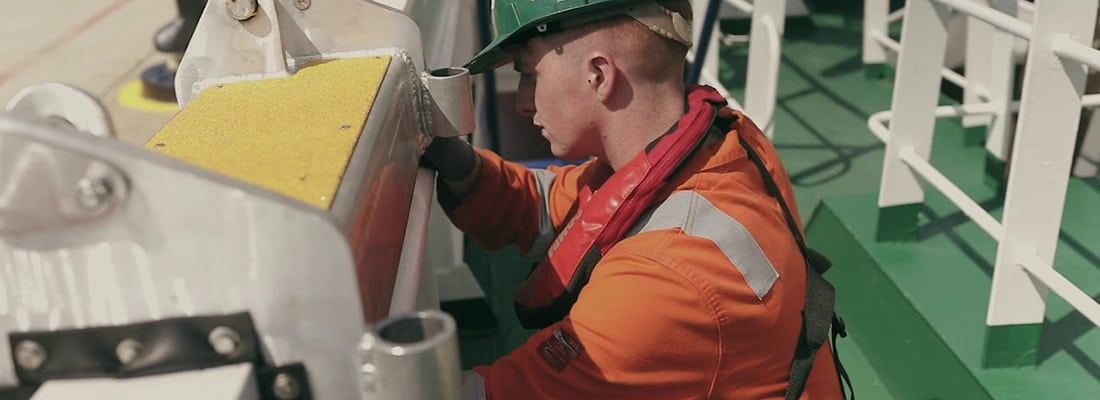 Engineer working on a ship in orange overalls