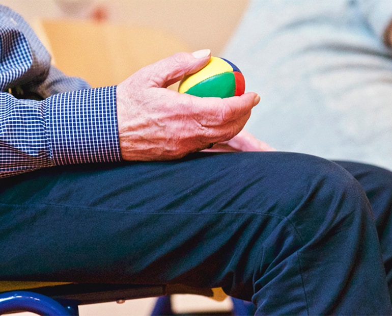 Elderly man holds coloured ball in his hand 