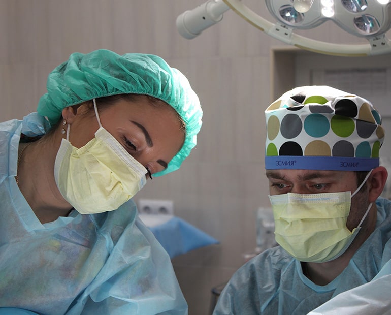 Male and female surgeons with face mask, gown and cap