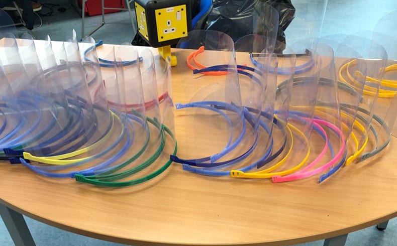 Selection of colourful 3D printed face visors sitting on a desk