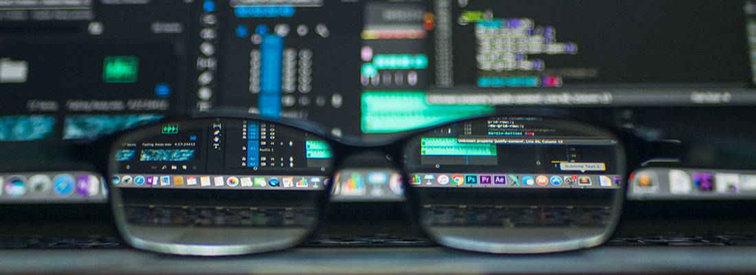 close up of a pair of glasses sitting in front of a computer monitor 