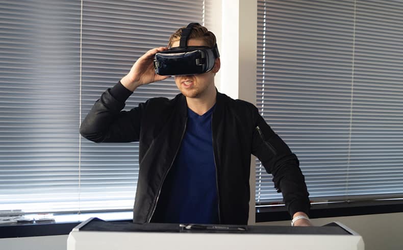 Male in black jacket and blue top wearing a VR headset