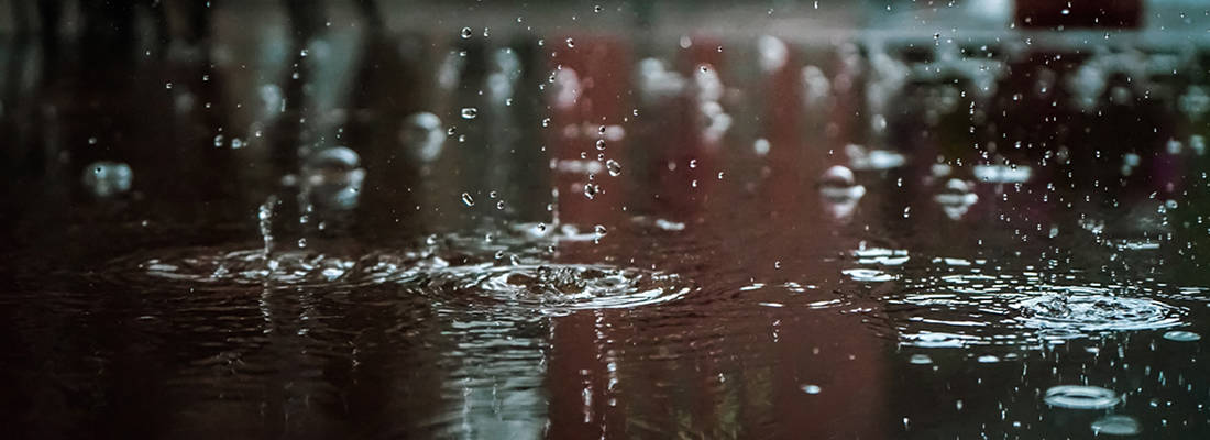 Rain falling into puddles on pavement 