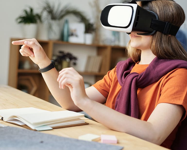 Female sitting at a desk with VR headset on her head