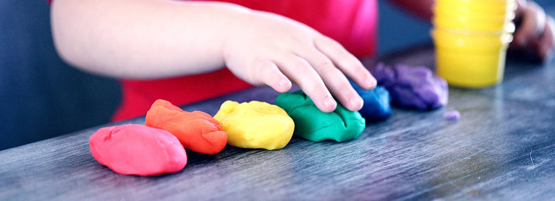 Close up of childs hand playing with colourful putty