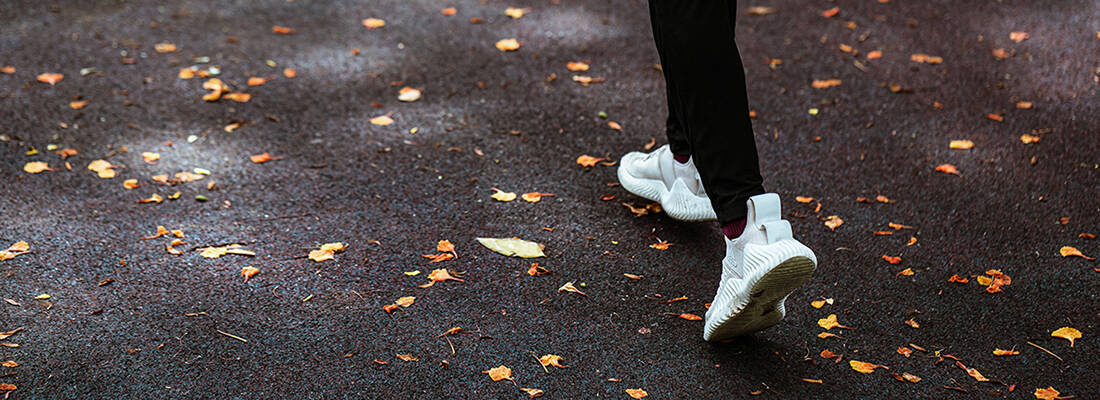 Close up of trainers on path with autumn leaves on ground