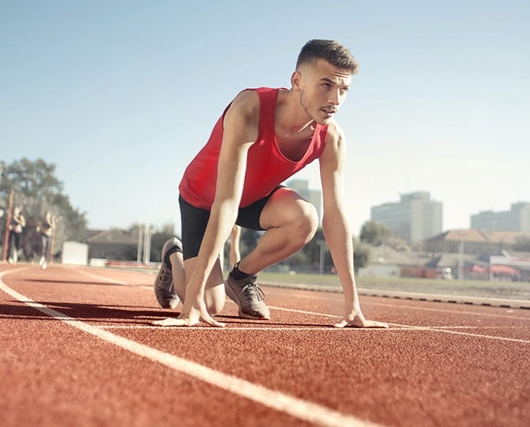 Male athlete in red running vest on start line