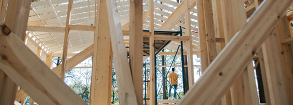 Man in yellow t-shirt looking upwards at a wooden roof