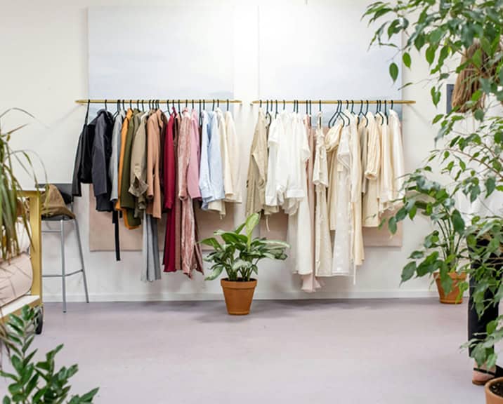 Row of hanging clothes with green plants to both sides