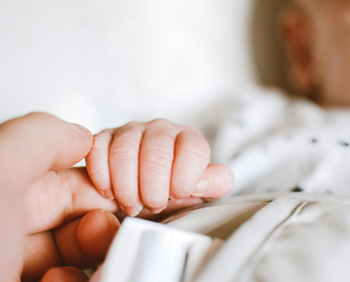 Close up of adult holding an infants hand