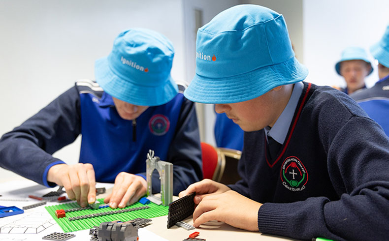 Two students wearing blue hats working with lego