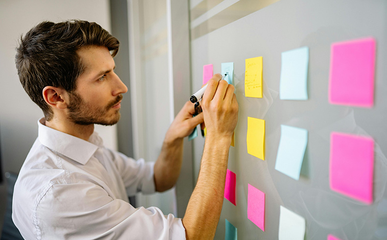 A Man in White Long Sleeve Button Up Shirt writing on post it notes