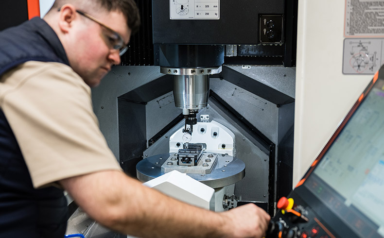 Man wearing safely glasses in front of CNC machine