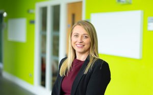 Melissa Doyle smiling at the camera standing in front of a green wall