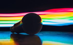 Colourful light traces behind a silhouette of a bulb